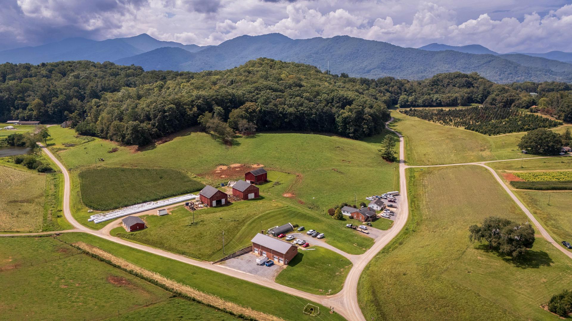 Aerial view of farm with green pastures and Blue Ridge Mountains in background